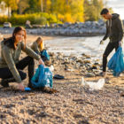 California: Young woman picking up garbage in bag at beach
