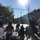 Syracuse: 4 people stand on street encircled by crowd