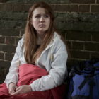 homelessness: Teenage girl sleeping on street, sitting against brick wall