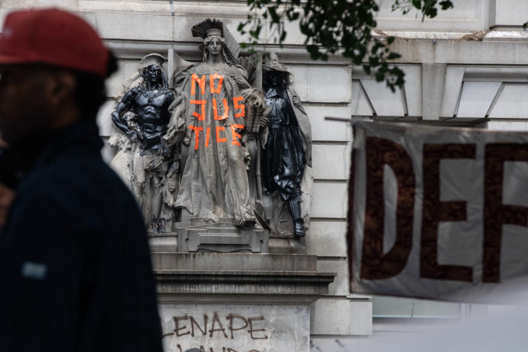 NYPD: Sculpture on building has no justice written on it with orange tape, graffiti below it