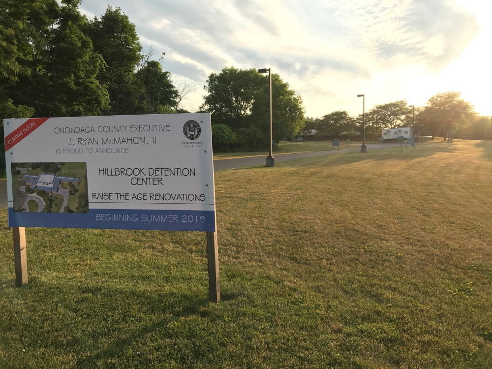 New York Raise Age: Big sign on grass says Hillbrook Detention Center raise the age renovations Tags: Hillbrook, Syracuse, Legal Aid Society, Children’s Defense Fund, raise the age, New York, legislation