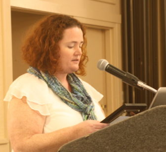 PPAL: Meri Viano (headshot), associate director of Parent/Professional Advocacy League, woman with curly red hair at podium wearing white top, scarf