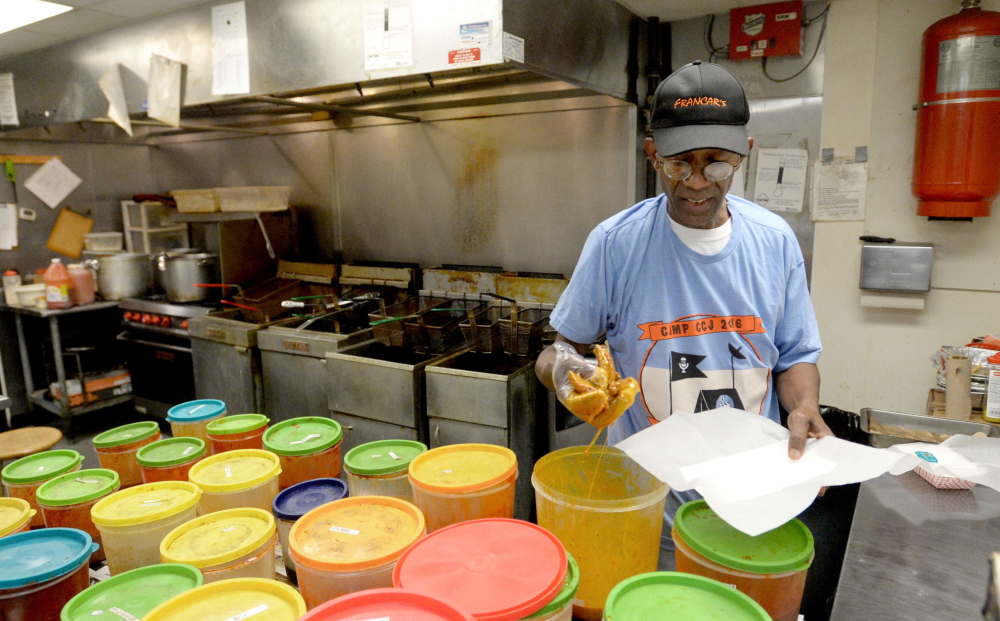 Macon: Man in ball cap, T-shirt dunking something in plastic tub in commercial kitchen