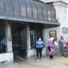Auburn: Women wearing masks, carrying bags wait on line outside building