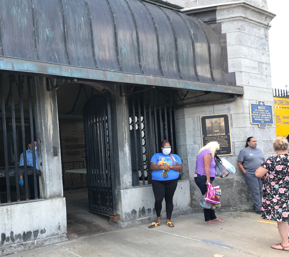 Auburn: Women wearing masks, carrying bags wait on line outside building