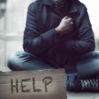 homelessness: Person sitting on the street with help sign