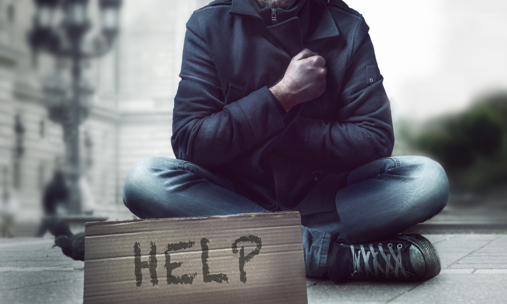 homelessness: Person sitting on the street with help sign