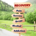 Rehabilitation concept. Wooden signboards pointing different directions to RECOVERY and ADDICTION on landscape background