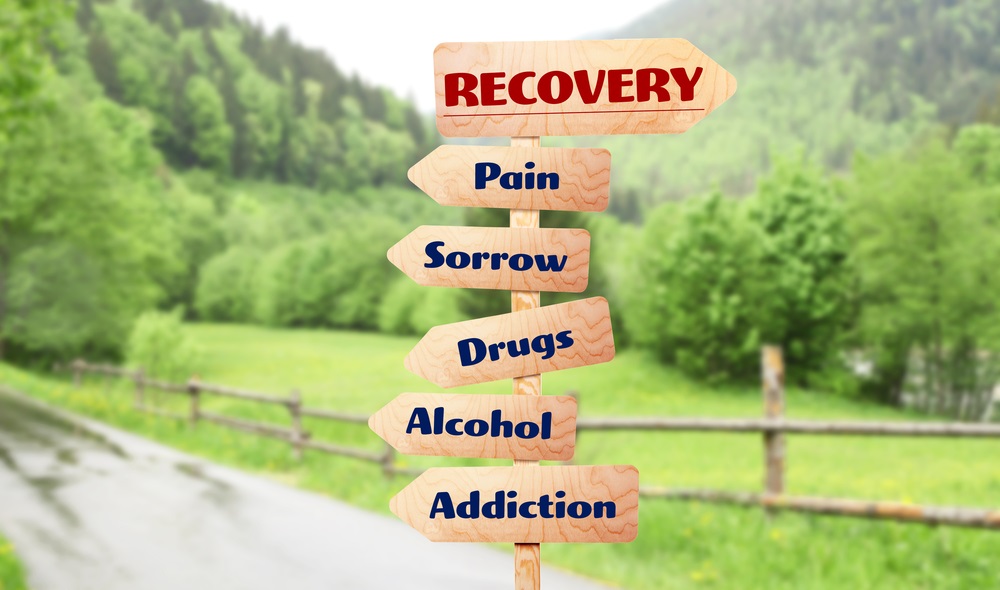 Rehabilitation concept. Wooden signboards pointing different directions to RECOVERY and ADDICTION on landscape background