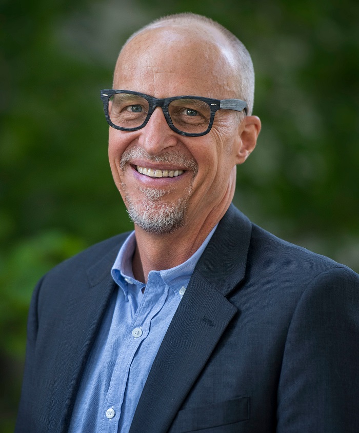philanthropy: Brian Malte (headshot), executive director of Hope and Heal Fund, smiling bald man with gray beard, mustache wearing glasses, dark blue jacket, light blue shirt 