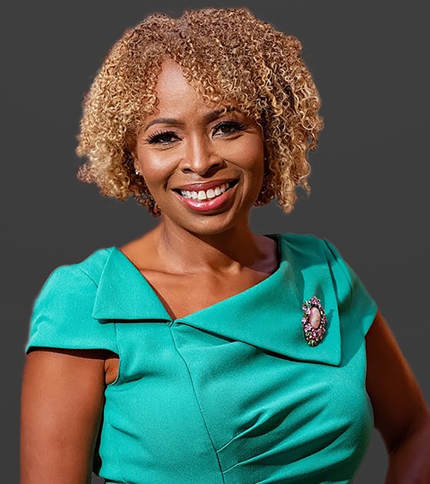 Jocelynne Rainey (headshot), CEO, president of GOSO, smiling woman with curly red hair in green dress with brooch