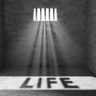 life sentence: Prison with light and shadow spelling out life through a barred window