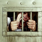 California: Yelling male grabs the bars of his jail cell.