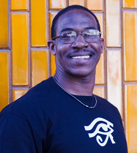 survival mode: Anthony Robinson (headshot), smiling man with short black hair, glasses, dark blue T-shirt with message I am working