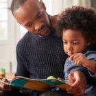 book club: Father And Young Son Reading Book Together At Home