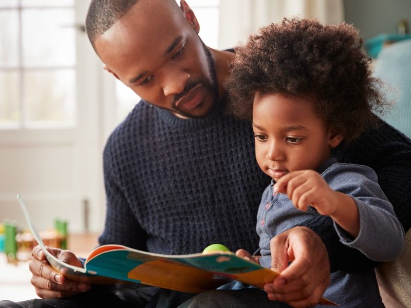 book club: Father And Young Son Reading Book Together At Home