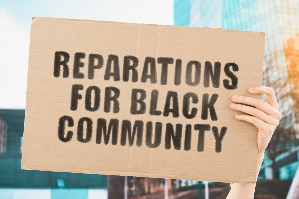 restorative justice: The phrase "Reparations for black community " on a banner in men's hand with blurred background.