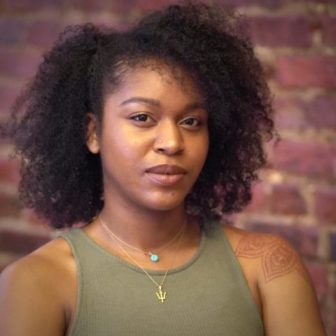 restorative justice: Sia Henry (headshot), senior program specialist with Impact Justice, woman with dark curly hair, necklaces, green tank top