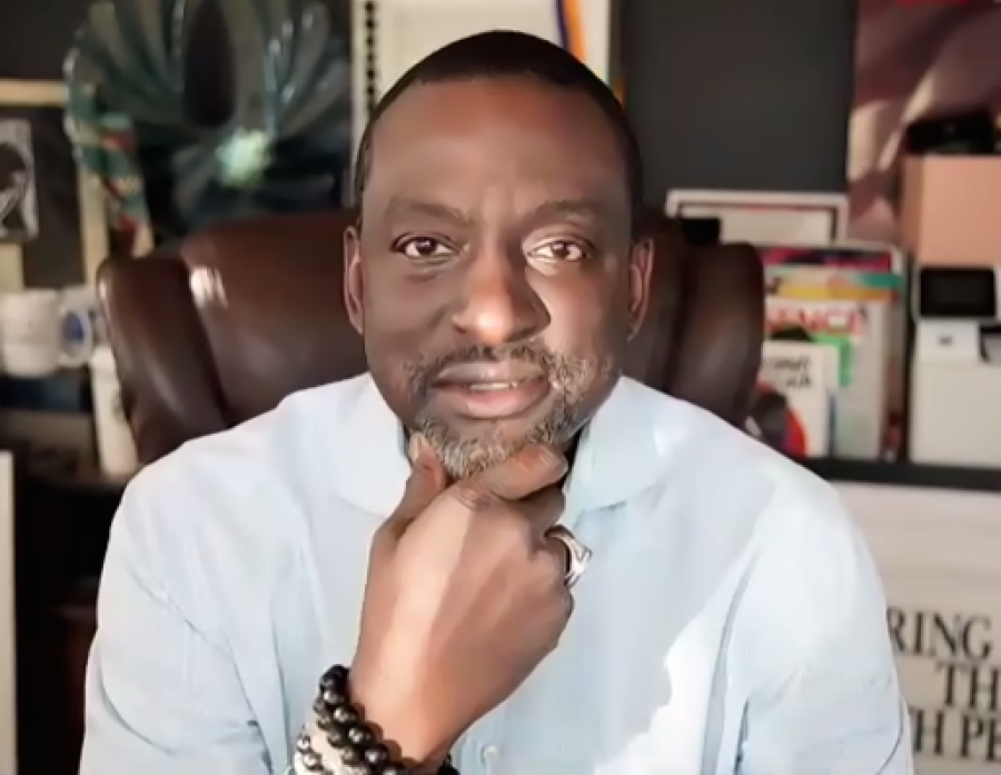 Youth Miranda Rights - Yusef Salaam headshot: Bearded, mustached man holds chin in hand in front of bookcase