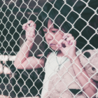Mexico border kids in cages: Lone child stands wit teddy bear holding onto chainlink fence.