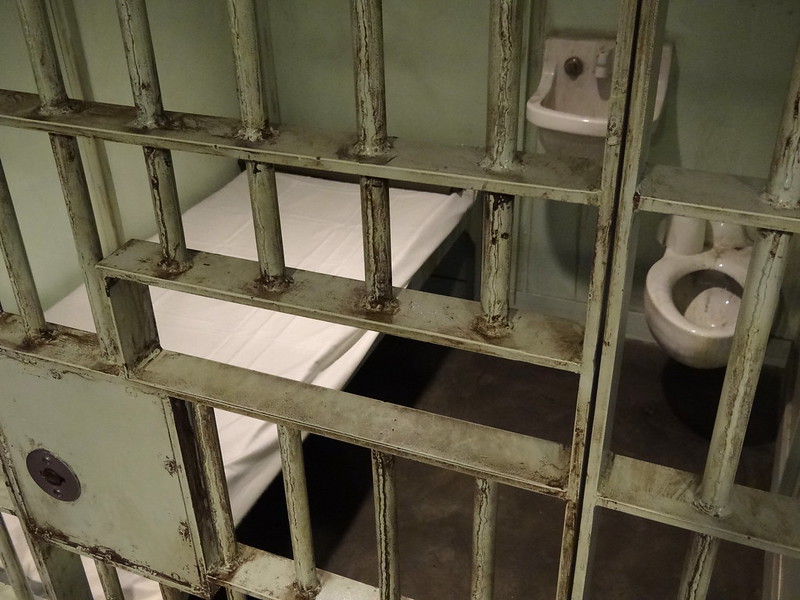 youth solitary confinement: closeup of jail cell door and interior with cot and metal toilet