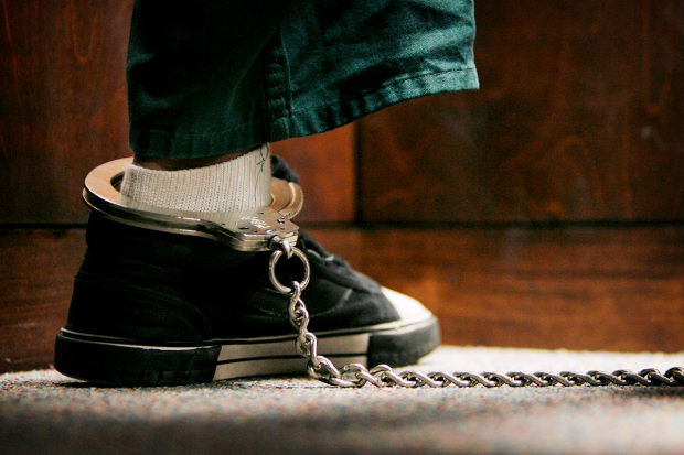 Juvenile crime statistics: Foot in black tennis shoe and white socks with silver metal restraining chain