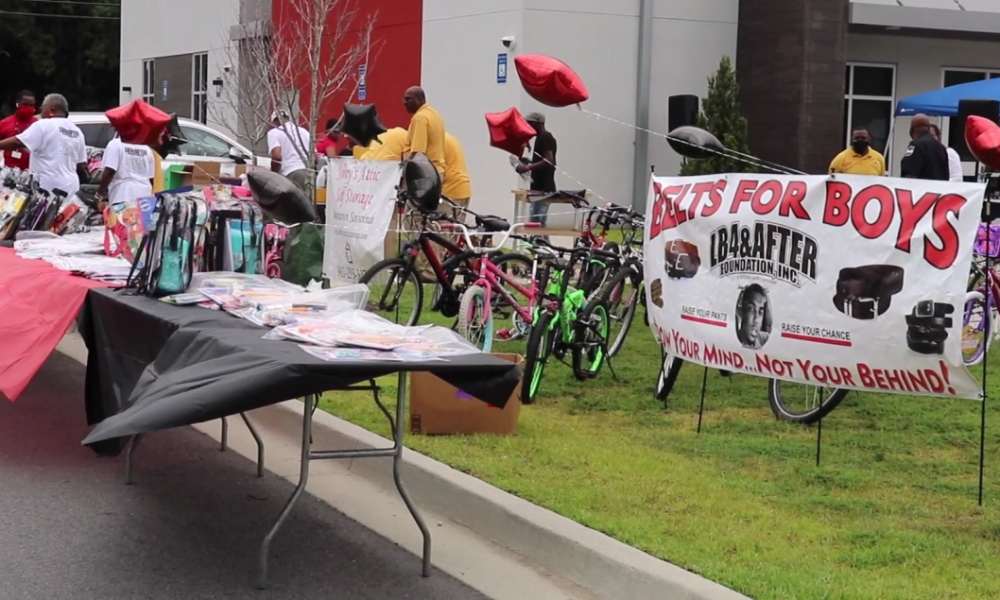 Savannah gun violence: Neighborhood folks gather at outdoor display tables with items for sale and a large sign with red and black text