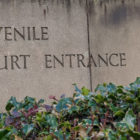 juvenile detention fees: stone sign for juvenile court entrance with flowers in front