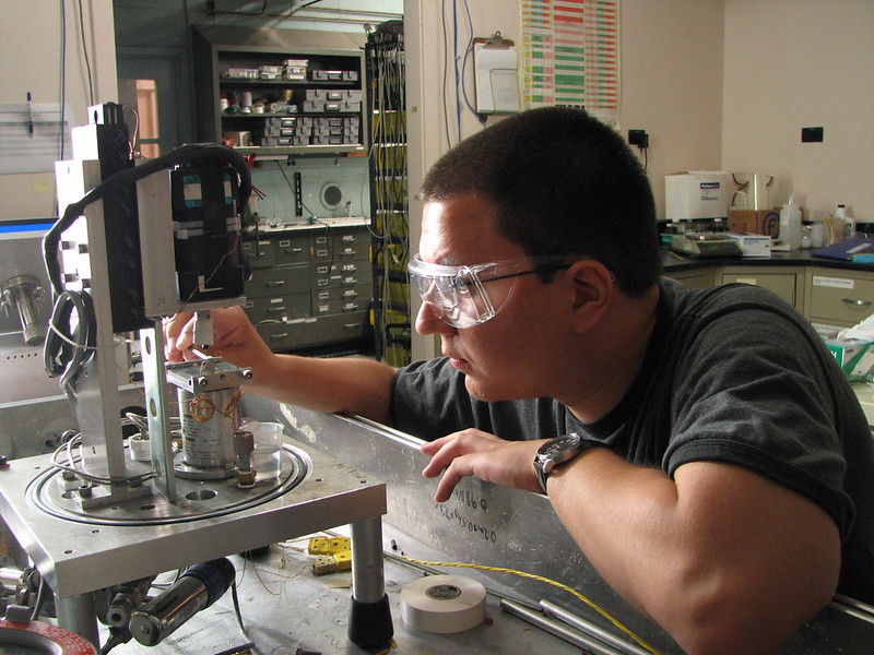 Young man wears goggles and tinkers with lab equipment