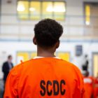 prisoners want more college prison programs: young black prisoner in orange garb looking at something