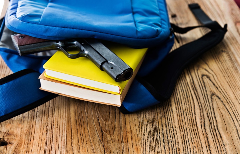 When students bring guns to North Carolina schools: gun falling out of backpack on top of yellow book