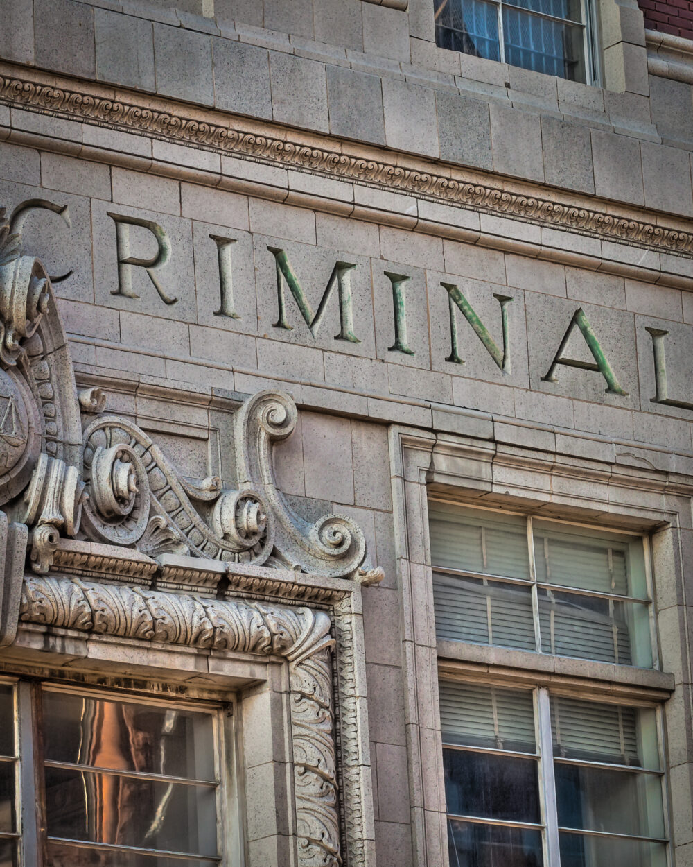 The word "criminal" is engraved on a building.