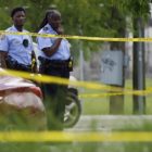 Public heath strategists tackle New Orleans gun violence: two Black cops looking at crime scene beyond yellow tape