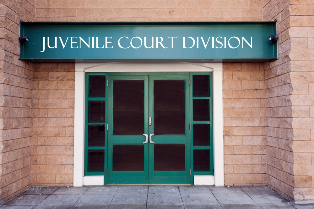 Juvenile court division entry with sign above white-framed, green double doors in red brick building