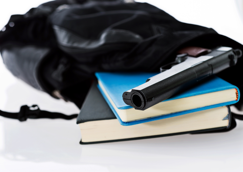 Guns in school: Hand gun and biiks sitting in open black backpack
