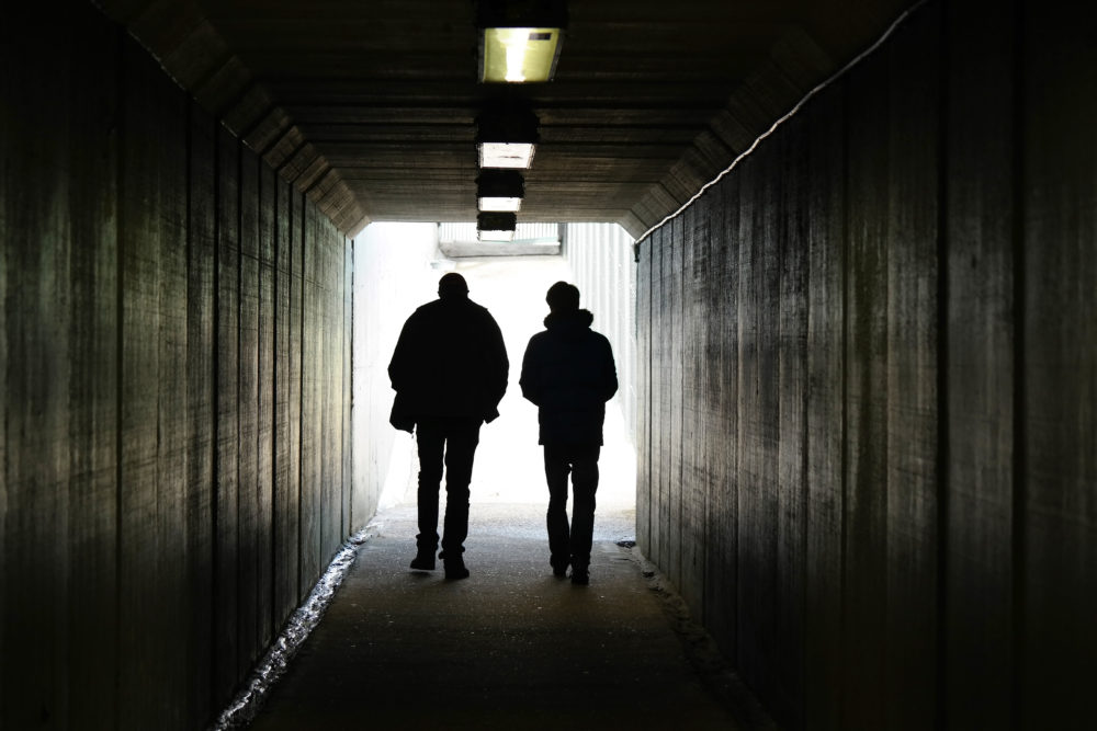Sex Offender Registry: Silhouette of two people walking away in a dark tunnel toward a lighted exit
