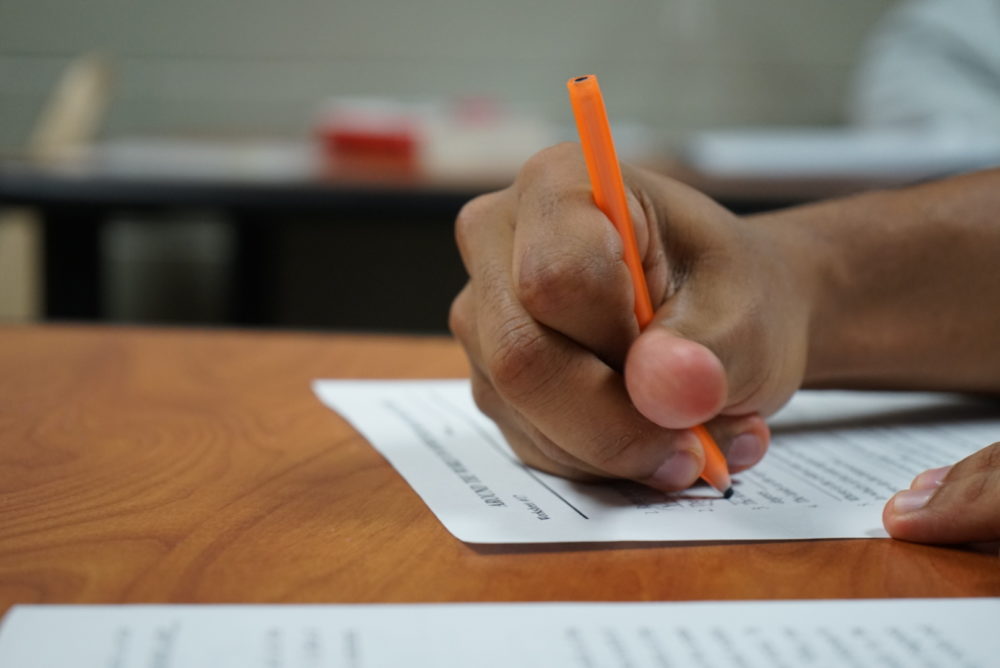 Utah Colleges Classes: Hans with orange pen writes in white paper