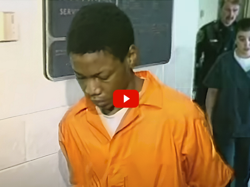 Teen Murder Sentence: Black teemn in orange prison jumpsuit with head down stands next to white cop in black uniform following