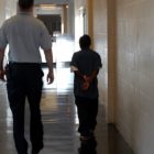 Disabled students at higher risk for arrests, dropping out: male detention worker walks a black juvenile offender down a hallway