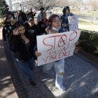 Denver school shooting suspect dead; parents push security: people marching down sidewalk with "Stop gun violence" sign
