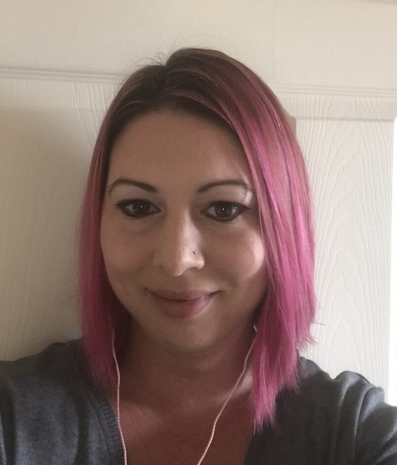 Drug Court: Young woman with bobbed pink hair wearing gray top smiles into camera
