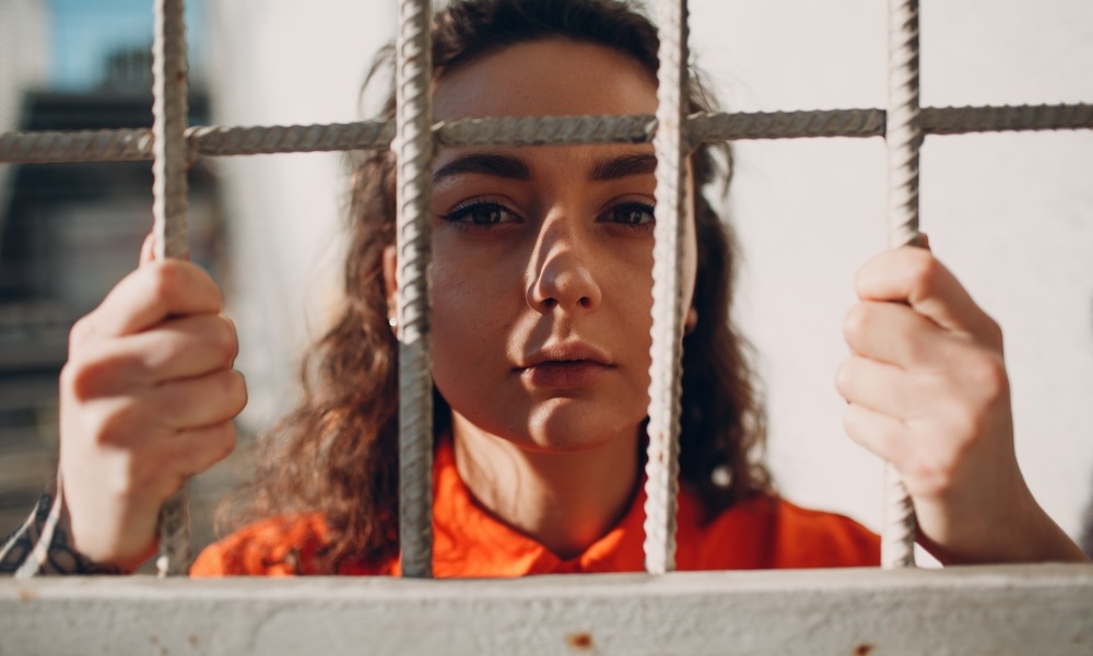 Girls in the juvenile justice system: girl looking through detention center bars