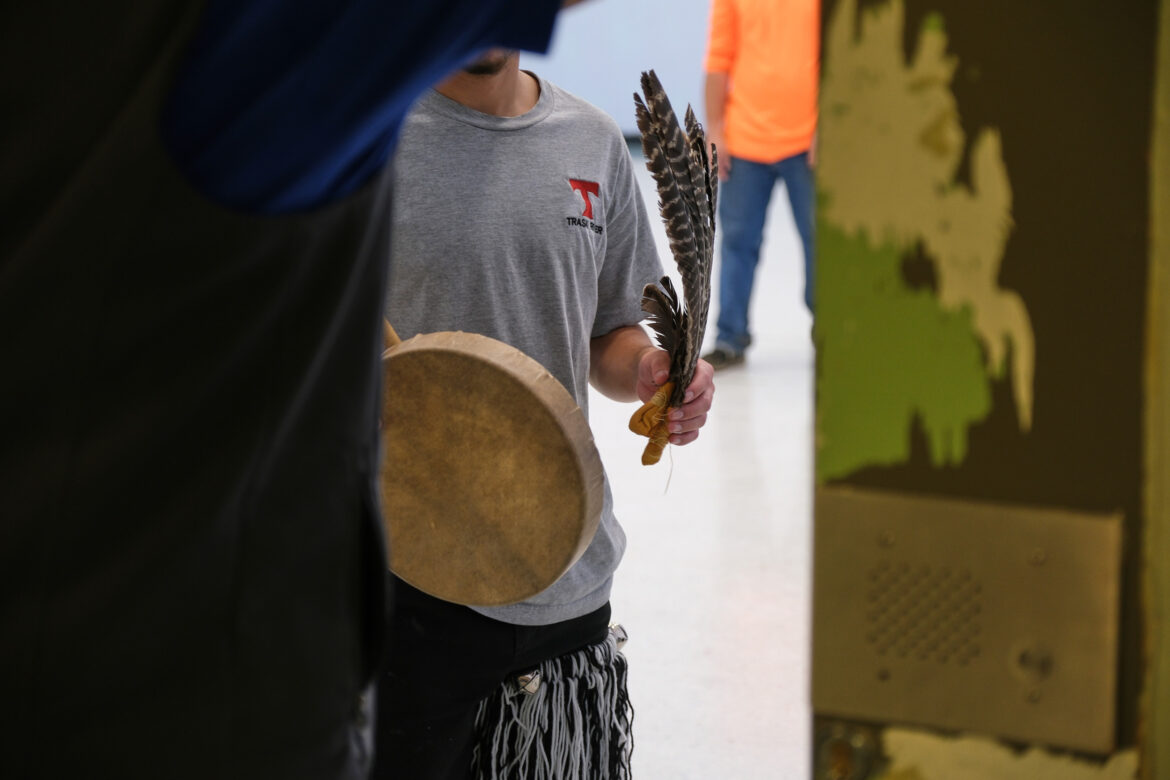Native American rituals: Close up of person walking toward camera holding a drum and two eagle feathers