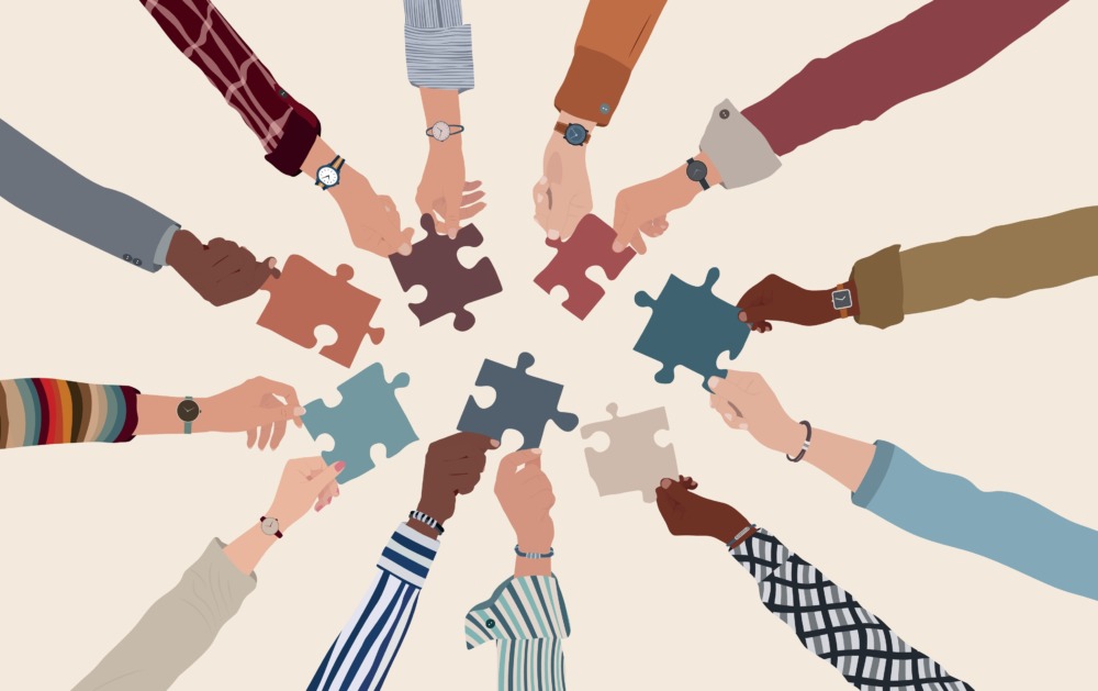 Alternatives to prison: Group of multicultural arms an hands forming circle reaching to each other with multi-colored puzzle pieces