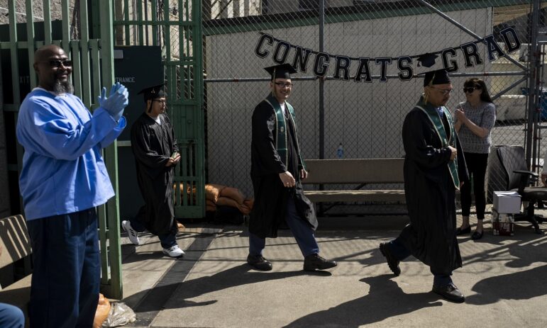 Free college for more prisoners: men in graduation garb walk past "Congrats Grad" sign while people clap