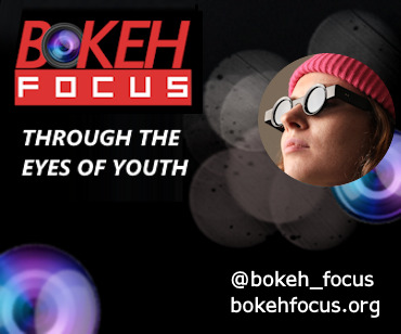 Red Bokeh Focus logo on black background with image of girl in pink hat and steampunk black glasses and text "Through the eyes of youth'