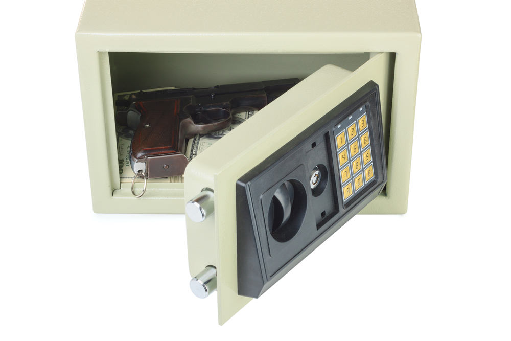 Gun Safety at Home: Small beige metal gun safe with black face and numeric keyboard on door that's open to show handgun and cash inside.