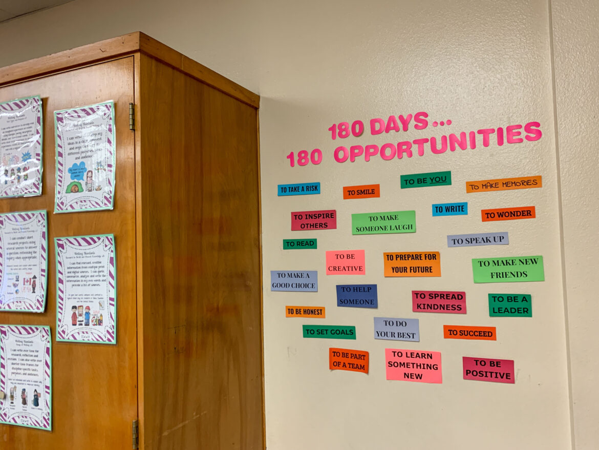 No school suspension: Bulleyin board next to tall light wood abinet with several large multi-colored labels under title "180 days — 180 Opportunities"