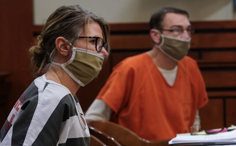Parents of teen charged in school shooting to stand trial: middle-aged white man and woman in facemasks sit at hearing