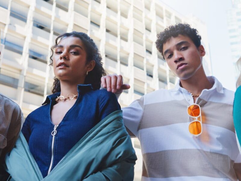 SYSTEM-INVOLVED YOUTH: FOUR TEENS WITH SERIOUS LOOKS ON THEIR FACES STAND NEXT TO EACH OTHER OUTSIDE IN FRONT OF A WHITE SKYSCRAPER